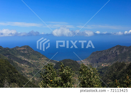 Landscape with mountains and green trees over blue sky and clouds 72113425