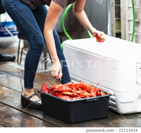 Worker grabbing freshly steamed Maine lobsters to serve at restaurant Worker grabbing freshly steamed Maine lobsters to serve at restaurant 72113834