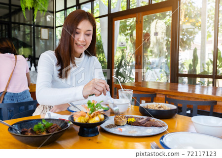 woman eating food in restaurant woman eating food in restaurant 72117123