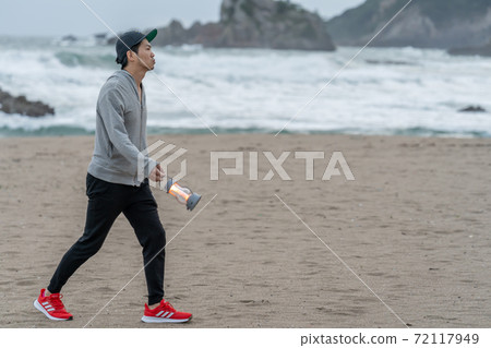 一個住在兩個地區的人，他的周末在清晨的海灘上散步 72117949