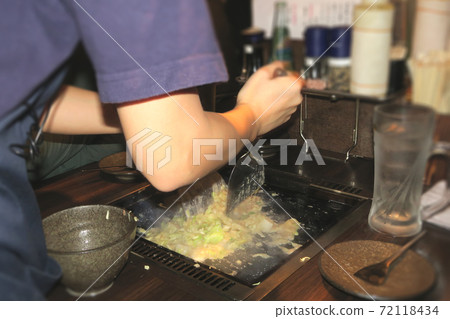 A part-time clerk who makes monjayaki on an iron plate at a customer table 72118434