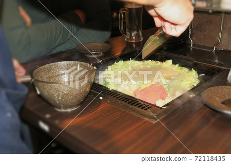 A part-time clerk who makes monjayaki on an iron plate at a customer table 72118435