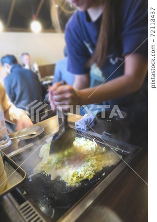 A part-time clerk who makes monjayaki on an iron plate at a customer table 72118437