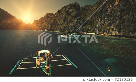Seascape with passenger boats at sunset in closeup aerial view. Cliff coast with trees at sun summer 72120126