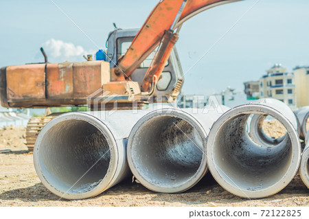 Stack of concrete drainage pipes for wells water discharges laying an external sewage system at a construction site outdoors warehouse. Civil infrastructure, industry manufacturing of cement products Stack of concrete drainage pipes for wells water discharges laying an external sewage system at a construction site outdoors warehouse. Civil infrastructure, industry manufacturing of cement products 72122825