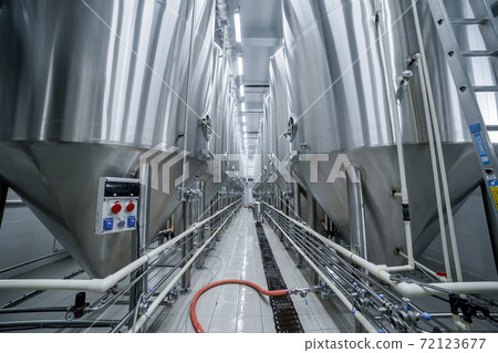 Row of tanks in brewery. Fermentation in brewery tanks with beer for brewing. Modern beer factory. Big steel tanks for storage. Row of tanks in brewery. Fermentation in brewery tanks with beer for brewing. Modern beer factory. Big steel tanks for storage. 72123677
