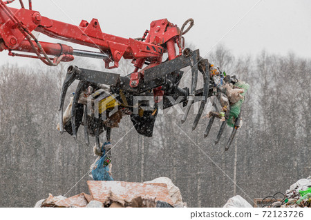 Recycling plant process of unloading garbage. Manipulator loads garbage on conveyor for further processing and sorting. Business for sorting and processing of waste. Recycling plant process of unloading garbage. Manipulator loads garbage on conveyor for further processing and sorting. Business for sorting and processing of waste. 72123726