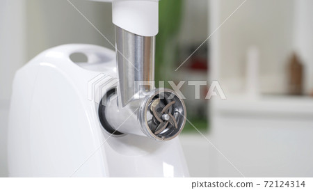 Female hand sets cutting plates in meat grinder for providing quality mince from all types of meat. Electric mincer machine for minced meat per minute, make sausages, mashed berries, squeeze juice. 72124314