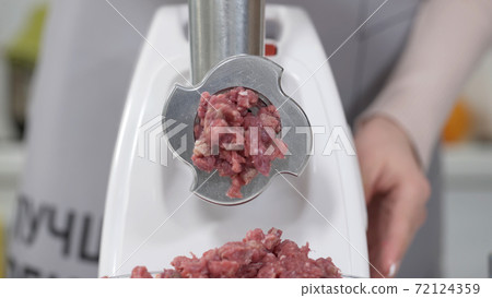 Making minced meat in an electric meat grinder from fresh beef at home. Pile of chopped meat. Electric mincer machine with fresh chopped meat. Preparation of minced beef with an electric meat grinder. 72124359