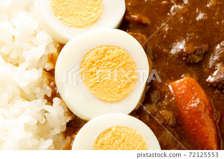 A slice of boiled egg on curry rice. 72125553