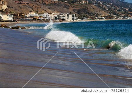 Heart shaped rock on beautiful sandy beach, cloudy sky, sun rays, reflections, and rolling waves in the blue hour just after sunrise. Heart shaped rock on beautiful sandy beach, cloudy sky, sun rays, reflections, and rolling waves in the blue hour just after sunrise. 72126834