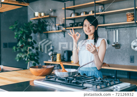 烹調的婦女,當觀看智能手機時 烹調的婦女,當觀看智能手機時 72126932