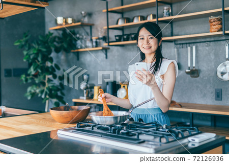 烹調的婦女,當觀看智能手機時 烹調的婦女,當觀看智能手機時 72126936