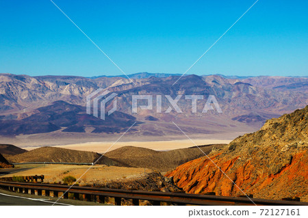 Winding road in Death Valley. Dry clay soil and a cloudless sky. Winding road in Death Valley. Dry clay soil and a cloudless sky. 72127161