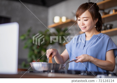 一個女人在看電腦的同時做飯 一個女人在看電腦的同時做飯 72128114