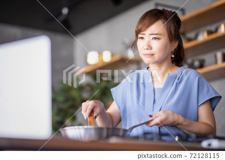 一個女人在看電腦的同時做飯 一個女人在看電腦的同時做飯 72128115