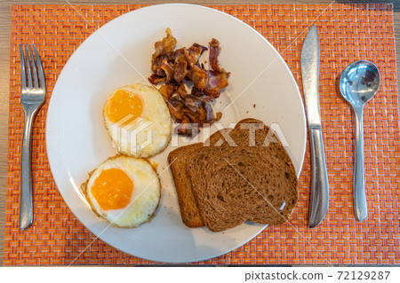 Top view of plate of sunny eggs with brown bread and ham Top view of plate of sunny eggs with brown bread and ham 72129287