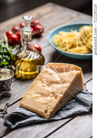 Big parmesan cheese slice on a table full of ingredients for Italian cuisine Big parmesan cheese slice on a table full of ingredients for Italian cuisine 72129319