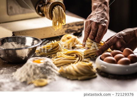 Hands of a chef twisting fettuccine pasta into nests after making a fresh dough from the ingredients Hands of a chef twisting fettuccine pasta into nests after making a fresh dough from the ingredients 72129376