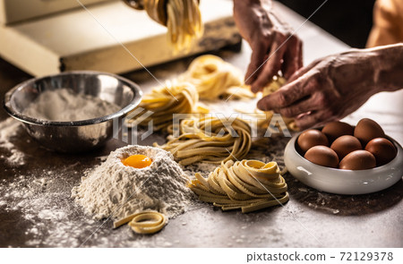 Hands of a chef twisting fettuccine pasta into nests after making a fresh dough from the ingredients 72129378