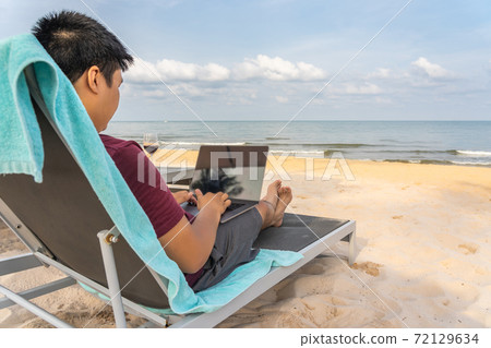 Asian freelancer working from home on laptop in the beach Asian freelancer working from home on laptop in the beach 72129634