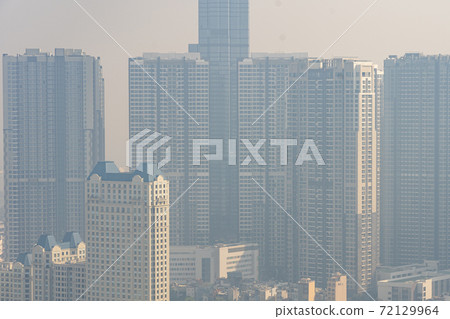 Tall buildings in industrial city with hazy polluted smog  72129964