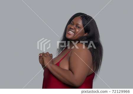 African american young woman in red underwear smiling and looking pleased 72129966
