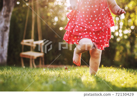 little girl's bare feet in the grass. little girl running at sunset 72130429