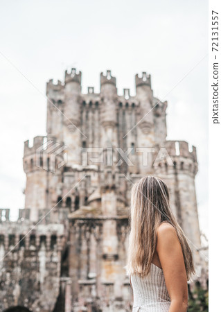 Young woman in front of a medieval castle Young woman in front of a medieval castle 72131557