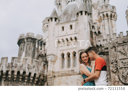 Young couple in front of a medieval castle Young couple in front of a medieval castle 72131558