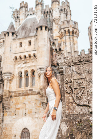 Young woman in front of a medieval castle Young woman in front of a medieval castle 72131565