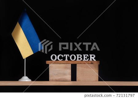 Wooden calendar of October with Ukrainian flag on black background. Dates in Ukraine in October 72131797