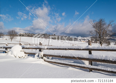 Alpine mountain snowy winter fir forest and snow drifts near wood fence on secondary countryside road wayside Alpine mountain snowy winter fir forest and snow drifts near wood fence on secondary countryside road wayside 72133184