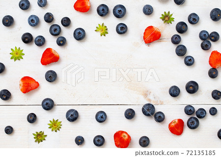Strawberries cut in half and blueberries arranged on borders of frame Strawberries cut in half and blueberries arranged on borders of frame 72135185