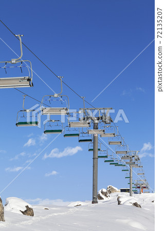 Chair-lift and snowy slope at ski resort on sun day 72135207