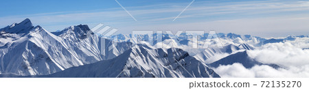 Panorama of snowy mountains in clouds Panorama of snowy mountains in clouds 72135270