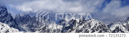 Panorama of snowy mountains in haze at sunny winter day 72135272