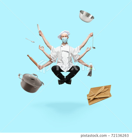 Young handsome multi-armed cooker in face mask levitating isolated on blue studio background with equipment 72136263
