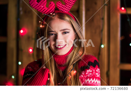 Beautiful girl with festive lights wearing red sweater Beautiful girl with festive lights wearing red sweater 72136680