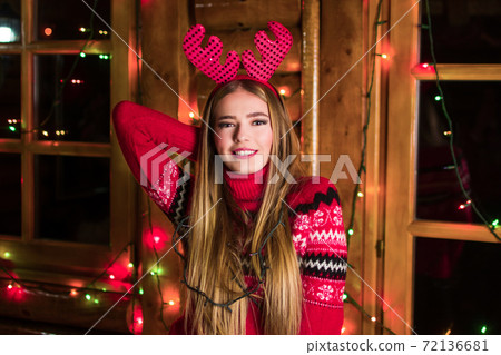 Beautiful girl with festive lights wearing red sweater Beautiful girl with festive lights wearing red sweater 72136681