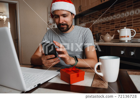 A hipster man with a red cup sitting at home at Christmas time. A hipster man with a red cup sitting at home at Christmas time. 72136728