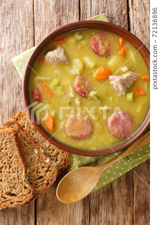 Dutch Split Pea Soup Erwtensoep with vegetables, sausages and pork closeup in the plate. vertical top view 72136896