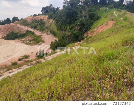 IPOH, MALAYSIA - MARCH 16, 2020: Permanent slope protection using the close turfing method to prevent erosion. The selected type of grass used for the method. The grass also stabilizes the slope IPOH, MALAYSIA - MARCH 16, 2020: Permanent slope protection using the close turfing method to prevent erosion. The selected type of grass used for the method. The grass also stabilizes the slope 72137343