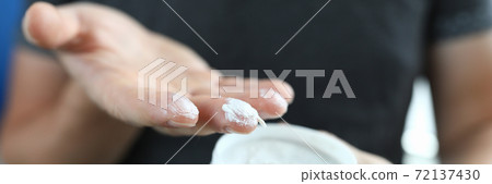 Man's hand holds jar with a white substance inside. Man's hand holds jar with a white substance inside. 72137430