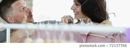 Man and woman are smiling at each other next to hanger with things 72137766