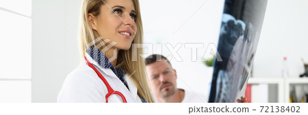 Female doctor is holding an x-ray next to sitting patient. 72138402