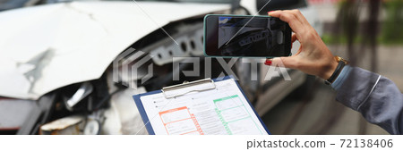 Woman photographs a broken car on smartphone and holds insurance documents in her hands Woman photographs a broken car on smartphone and holds insurance documents in her hands 72138406