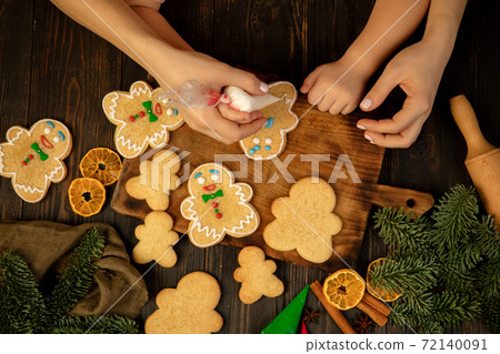 Close-up child and female hands decorating festive cookies and gingerbread men. 72140091