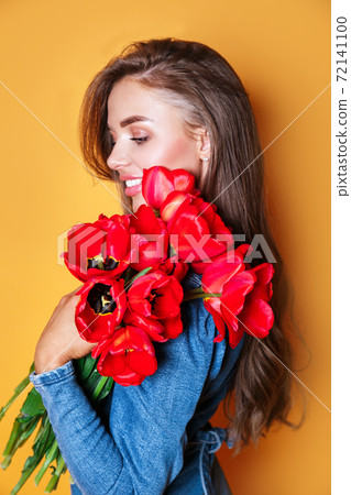 Portrait of a young beautiful woman with red flowers 72141100