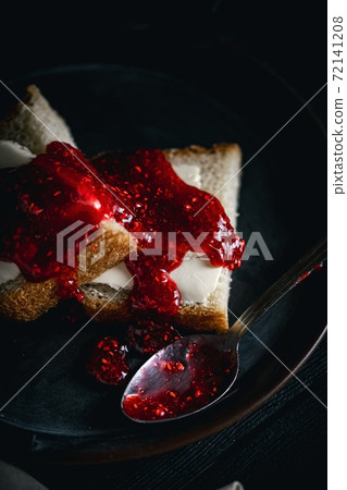 Sandwich with butter and raspberry jam on a dark plate with a dark background. Bread with butter and jelly in a black plate on a black background. Sandwich with butter and raspberry jam on a dark plate with a dark background. Bread with butter and jelly in a black plate on a black background. 72141208